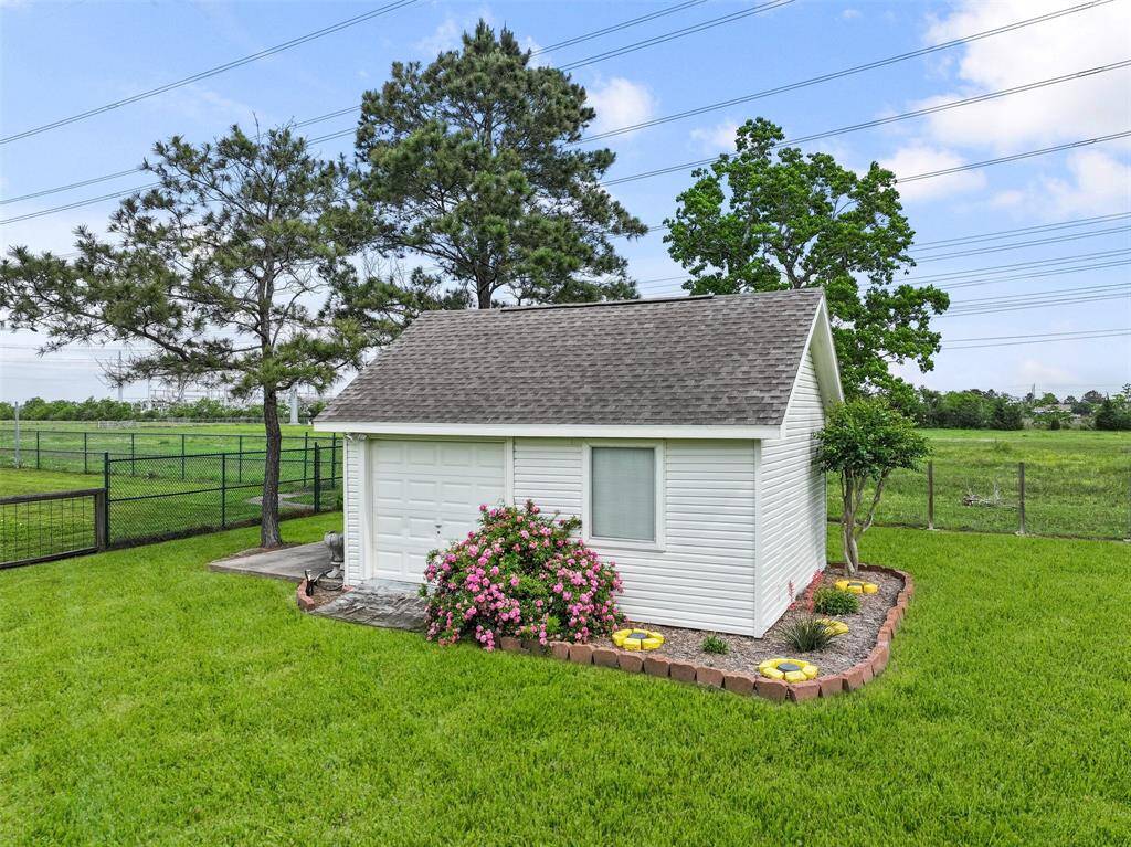 At the rear corner of the property, there is a flex-use storage building that can be used to house yard equipment, serve as a garden house, or even become a she-shed! Note the bay door, concrete pad, and landscape beds around it.