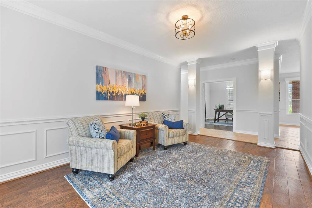 Off of the opposite side of the foyer and across from the study, you'll find an inviting foyer anchored by a pair of pillars with updated sconce lighting, ornate moldings, fresh neutral paint, luxury vinyl plank floors, and a stylish light fixture.