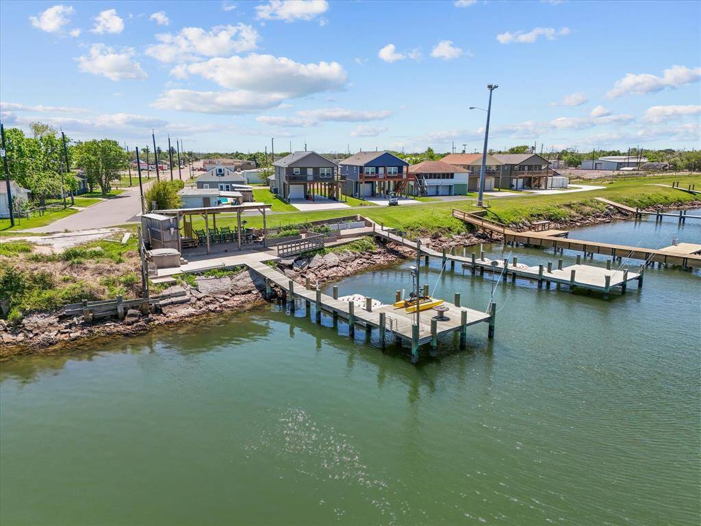 This photo showcases a waterfront property with boat docks, a shaded outdoor area, and nearby homes. The setting is serene, offering direct water access and a peaceful neighborhood vibe.
