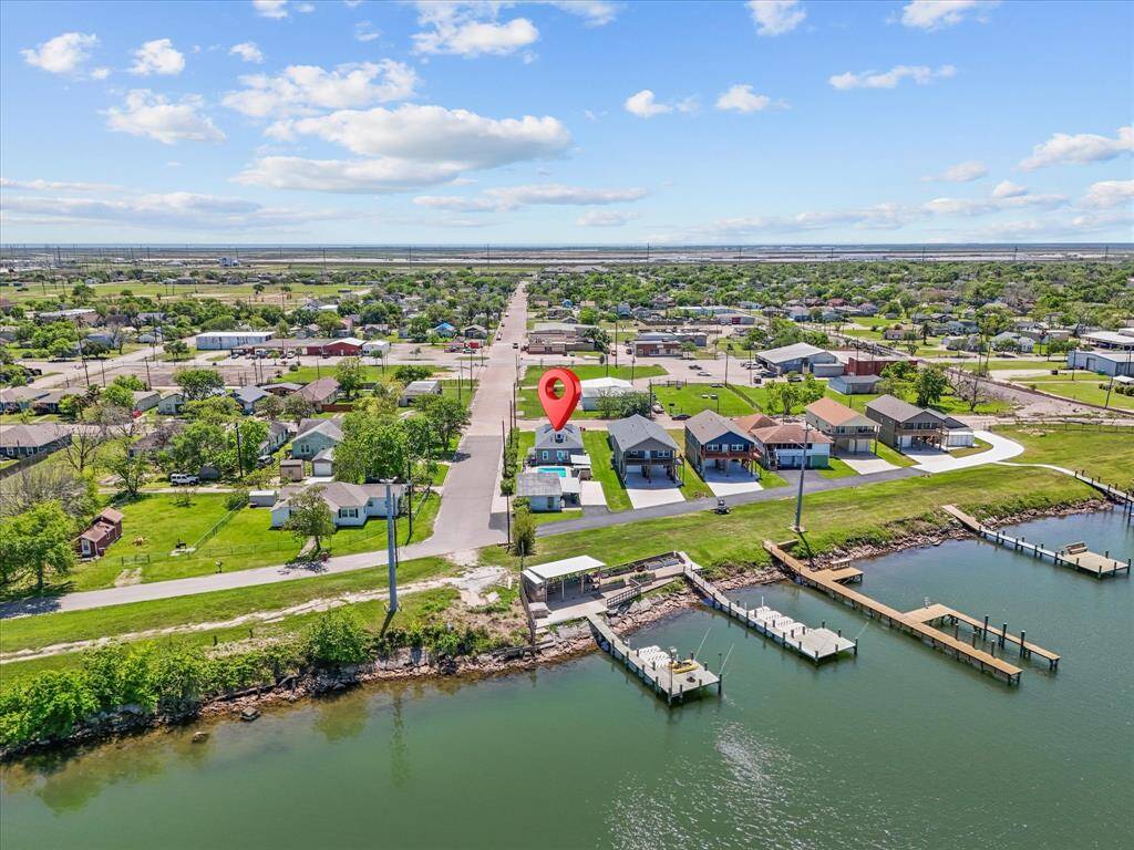 This aerial photo showcases a charming waterfront neighborhood, featuring a series of well-maintained homes with direct access to the water. The area is lush with greenery and has a serene atmosphere, ideal for those seeking a tranquil lifestyle with convenient docking facilities nearby.