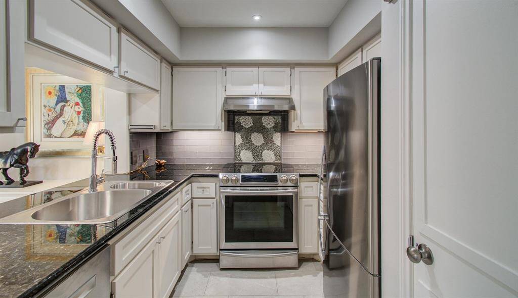 Completely renovated kitchen with tray ceiling and stainless appliances including French door refrigerator.  Full sized pantry door on right.