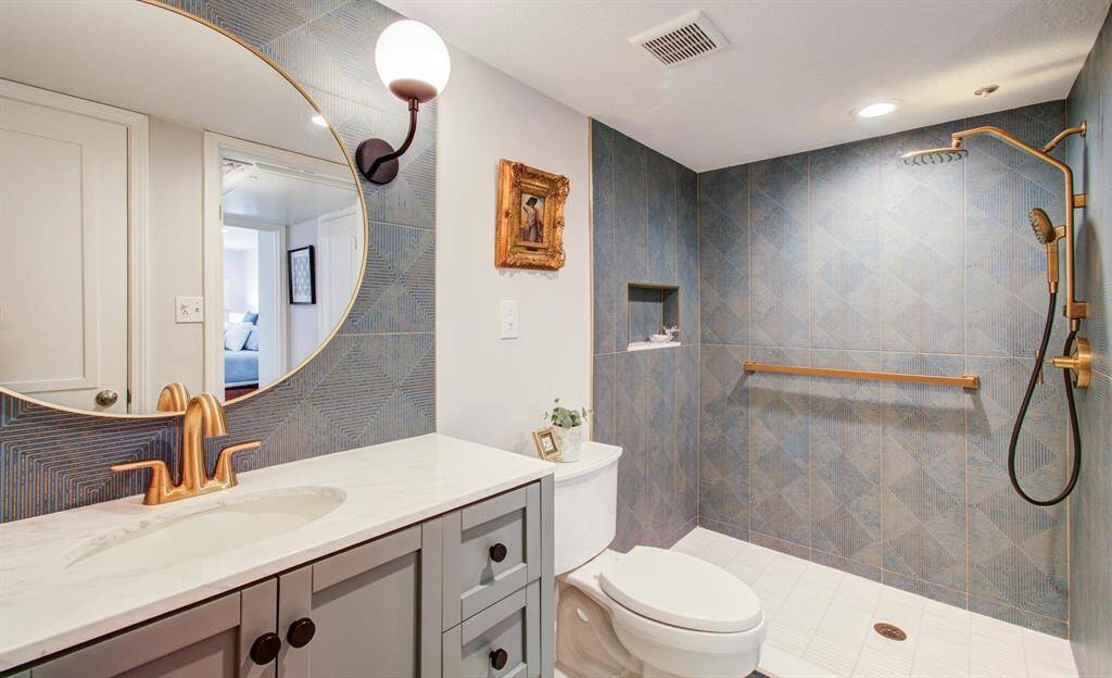 This luxurious custom bath has designer hardware, rainfall showerhead, floor to ceiling tile and ample storage.