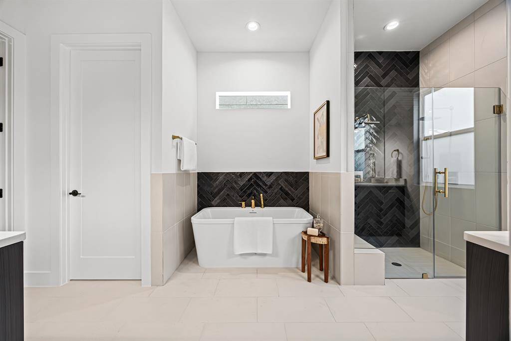 This elegant bathroom features a sleek freestanding bathtub, a modern glass-enclosed shower with stylish herringbone tiles, and minimalist decor, creating a spa-like atmosphere.