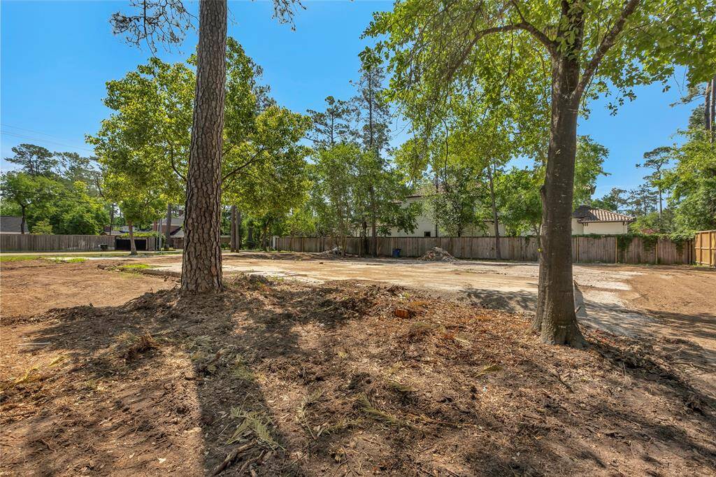 This photo shows a spacious, cleared lot with some mature trees around the perimeter. It has a fenced boundary and appears ready for construction, located in a quiet neighborhood setting. Ideal for building a custom home.