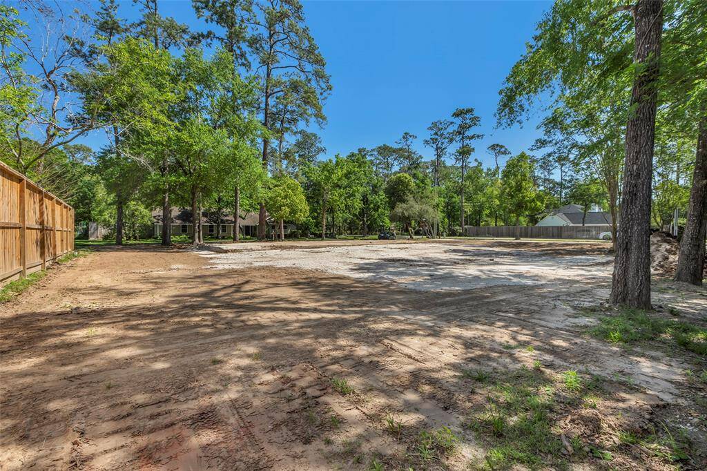 This photo shows a spacious, cleared lot with some mature trees around the perimeter. It has a fenced boundary and appears ready for construction, located in a quiet neighborhood setting. Ideal for building a custom home.