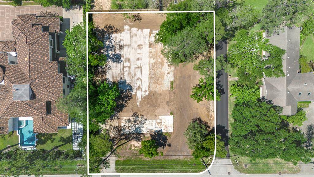 This photo shows a spacious, cleared lot surrounded by mature trees, with a wooden fence at the back. It's located in a quiet, residential area with neighboring homes visible, offering a serene setting with ample  potential for development.