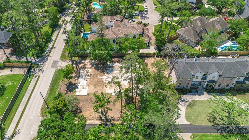 This photo shows a spacious, cleared lot surrounded by mature trees, with a wooden fence at the back. It's located in a quiet, residential area with neighboring homes visible, offering a serene setting with ample  potential for development.
