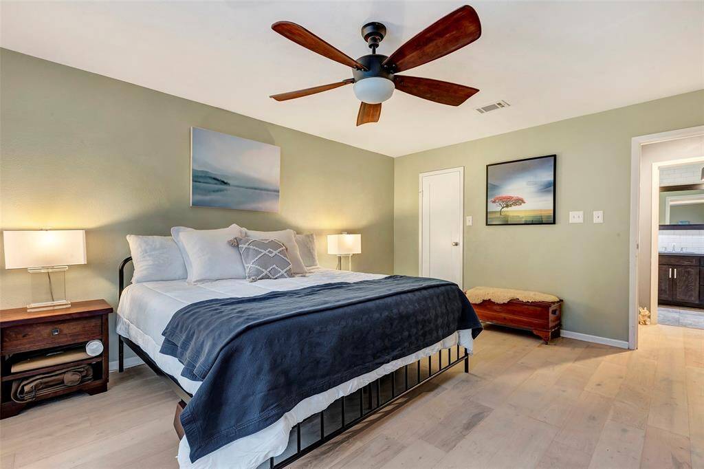 The bedroom features a modern ceiling fan, soothing green walls, and light vinyl plank flooring.