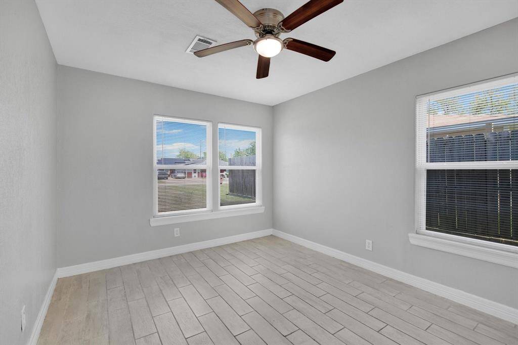 Bright and airy bedroom featuring large windows, sleek tile flooring, and a modern ceiling fan. Perfect for a cozy retreat or home office.