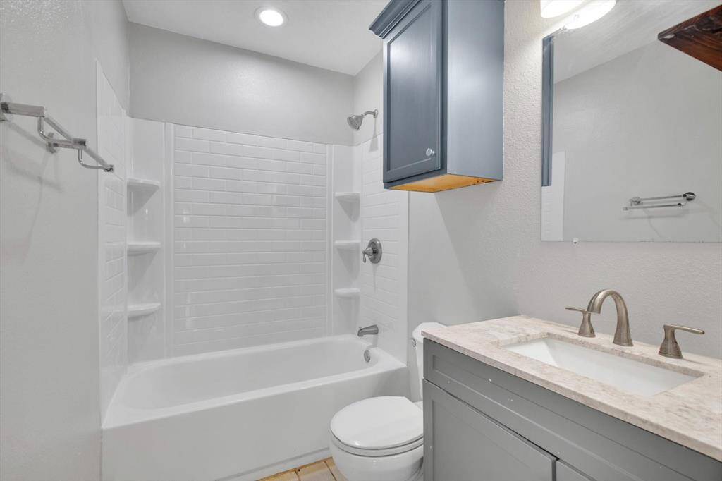 Bright and modern bathroom featuring elegant fixtures, a sleek vanity, and a pristine shower-tub combo with built-in shelving.