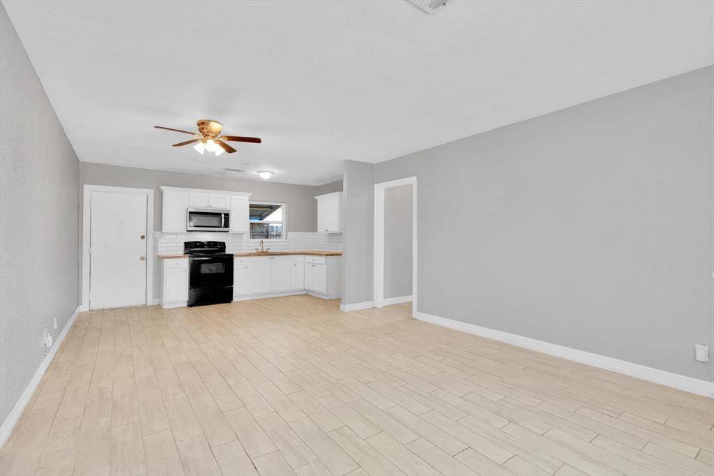 Welcome home to a spacious open-concept entryway and living area, featuring a modern kitchen with sleek finishes.
