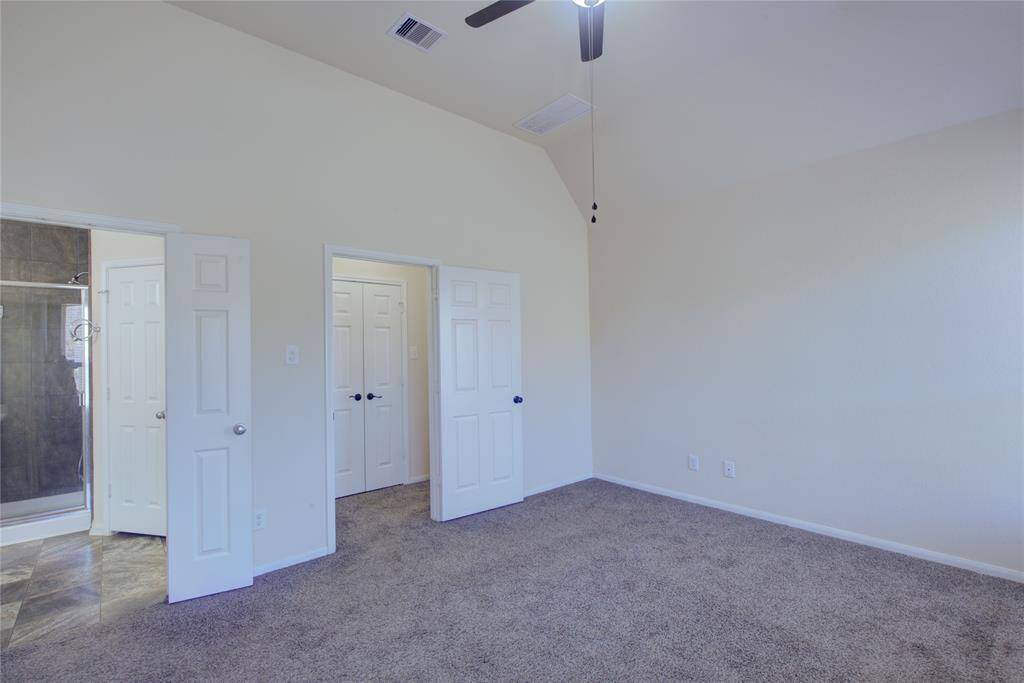 Primary bedroom with vaulted ceiling and fan/light