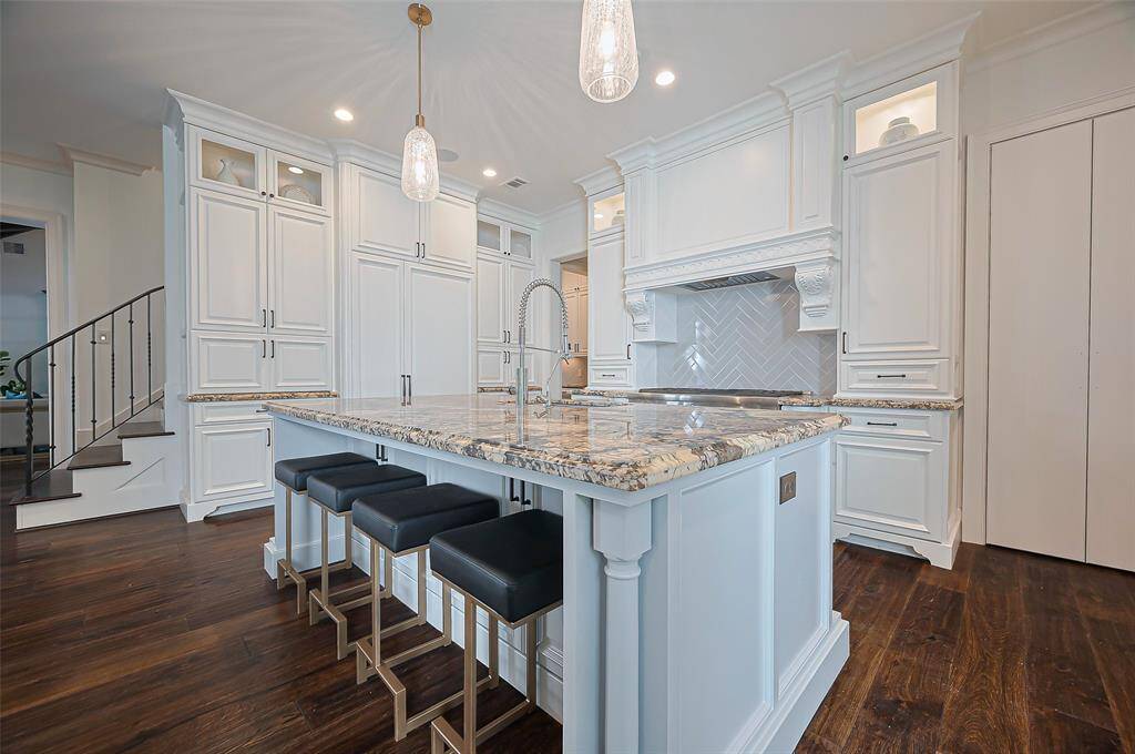 Kitchen offers tons of storage, a large island with seating, and modern pendant lighting. The herringbone backsplash and dark wood floors add a touch of sophistication. Cook and entertain with easy.