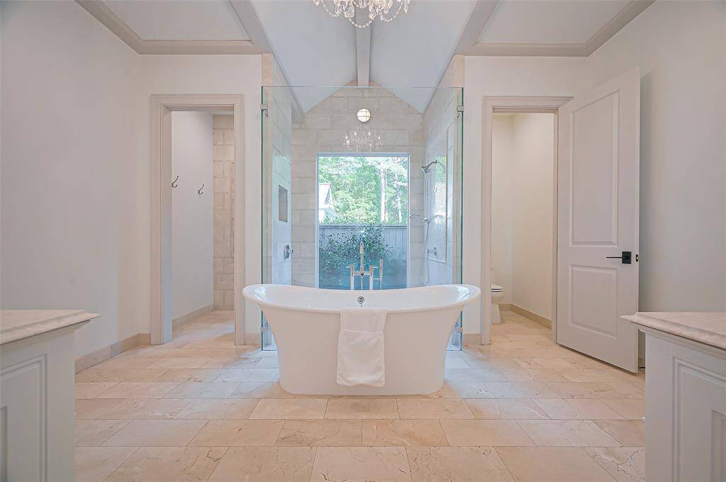 Beyond impressive Primary bathroom, featuring a freestanding tub big enough for two, large glass-enclosed shower, and dual vanities. The room is bright with neutral tones and a chandelier, creating a luxurious retreat.