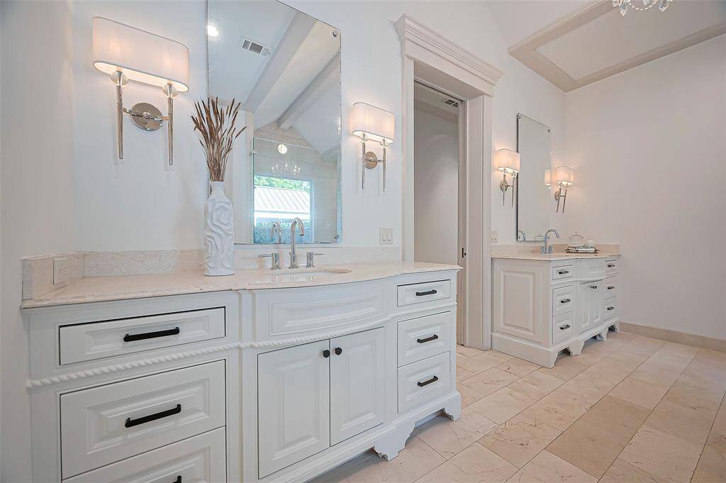 Two beautiful vanities, custom cabinetry marble countertops, and chic wall sconces.