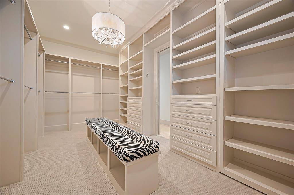 Primary walk-in closet features ample shelving, hanging space, and drawers for storage.