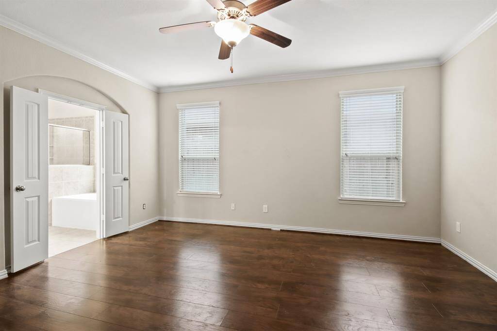 Spacious primary bedroom located on the first floor, featuring high ceilings, an ensuite bathroom, and plenty of open space.