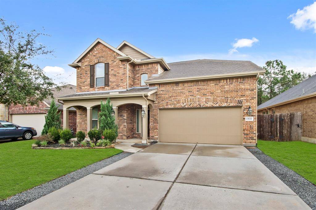 Double-wide driveway with an attached garage and well-maintained landscaping.