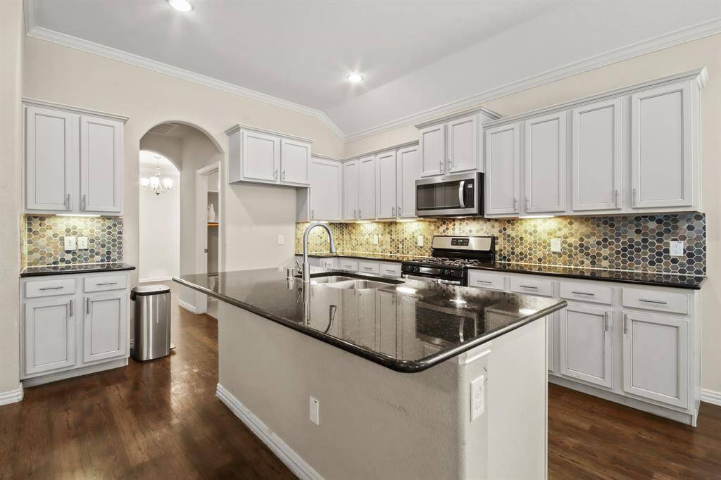 Beautiful open-style kitchen featuring granite island countertops, stainless steel appliances, ample cabinetry, and generous pantry space.