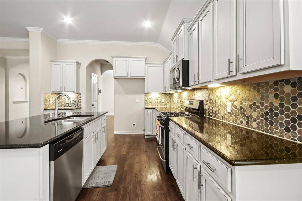 Beautiful open-style kitchen featuring granite island countertops, stainless steel appliances, ample cabinetry, and generous pantry space.