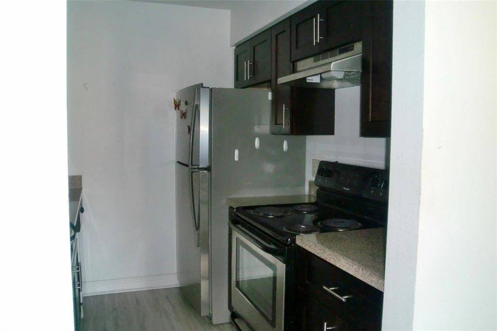 Sleek kitchen with modern stainless steel appliances, dark wood cabinets, and stylish countertops.
