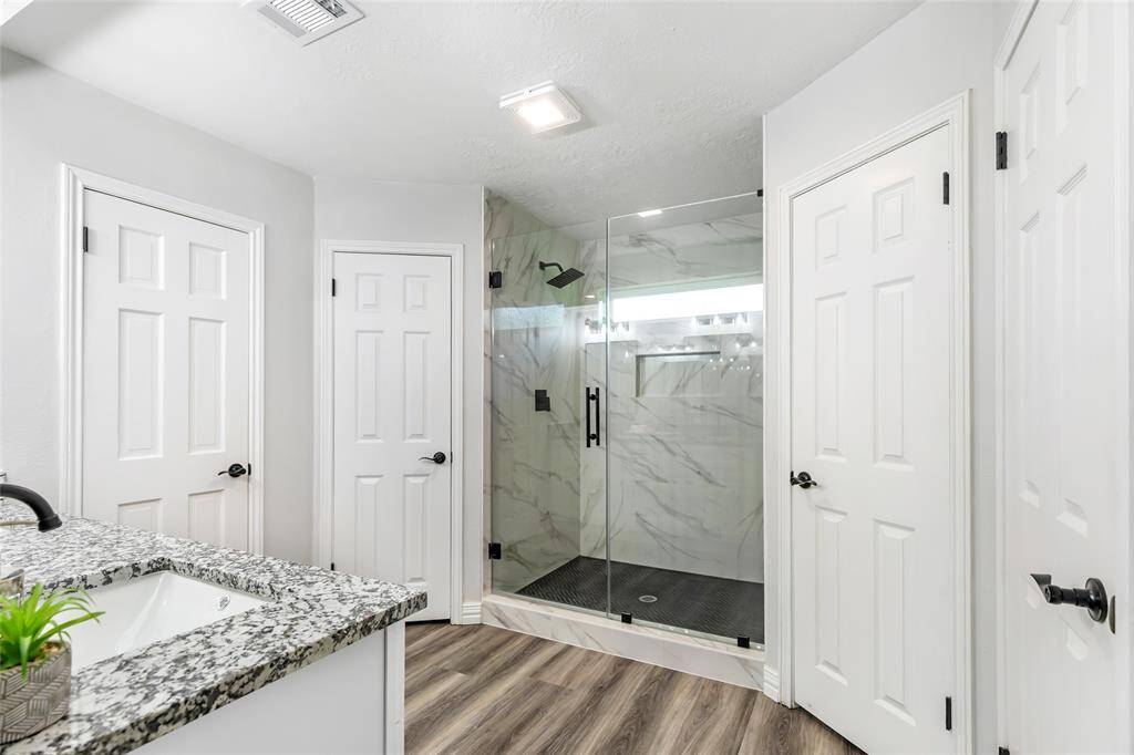 Primary bathroom with seamless glass shower and dual walk-in closets.