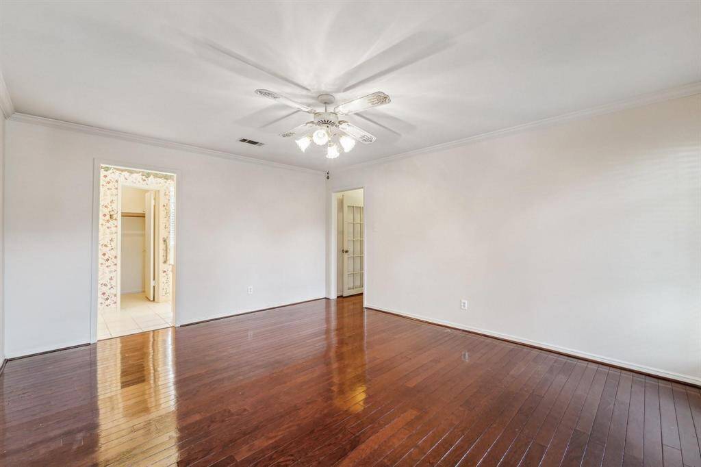 The downstairs Primary bedroom features freshly polished flooring and large windows for natural light.