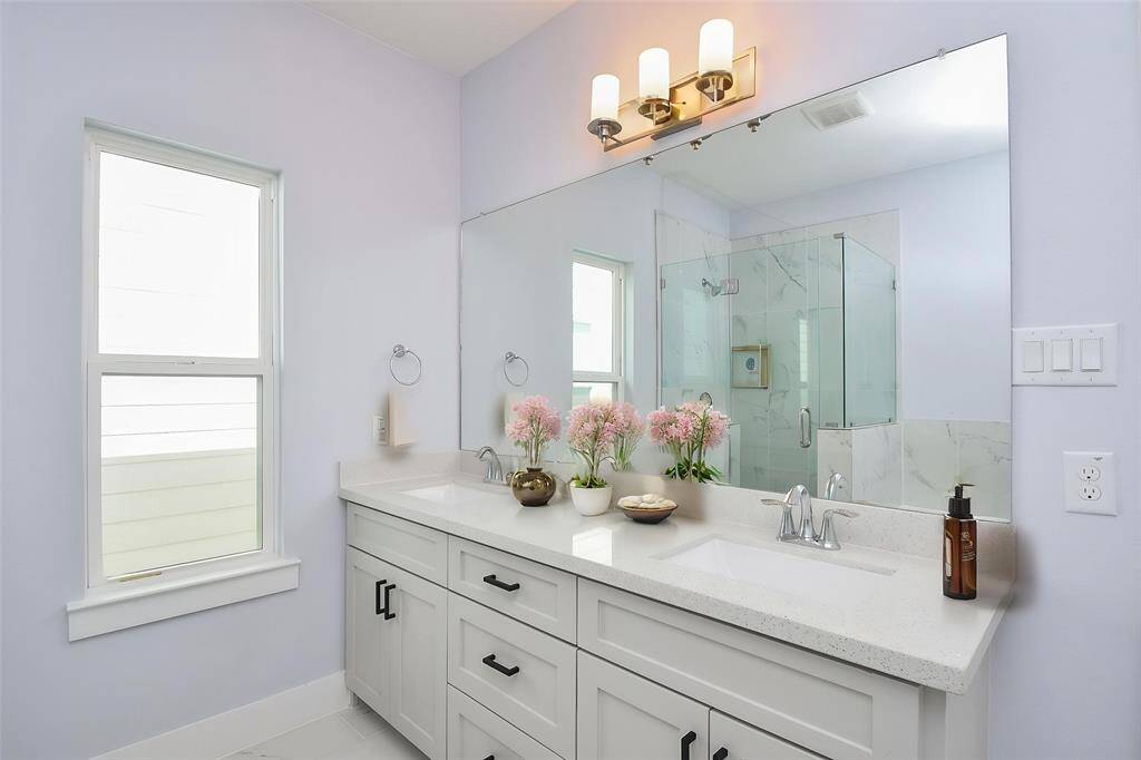 The primary bath vanity includes double sinks, a chic mirror, and ample storage space.