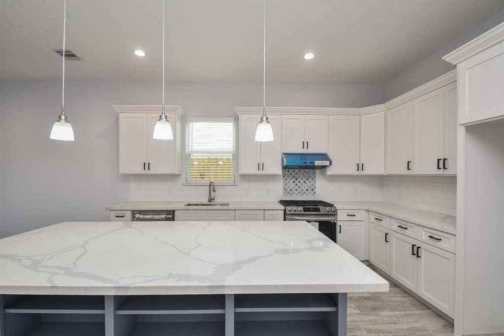 The large island in this beautifully designed kitchen is complemented by quartz countertops and plenty of cabinet and storage space.