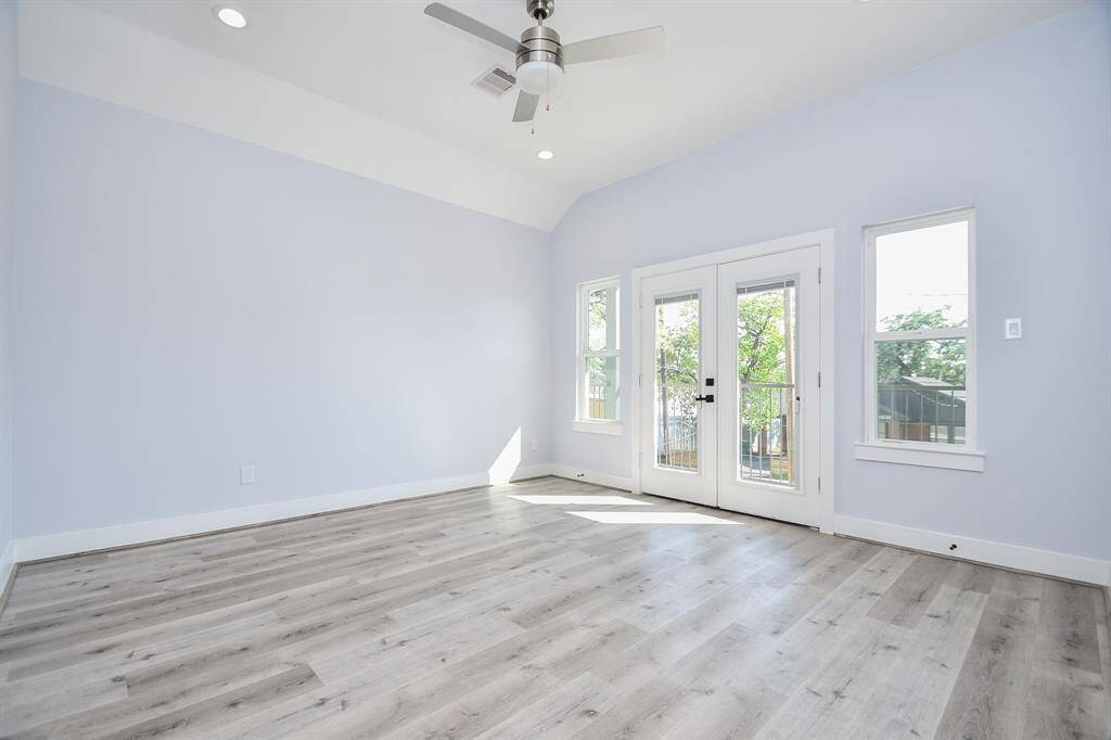 The spacious primary bedroom features high ceilings and double glass doors that lead to the balcony, creating a seamless indoor-outdoor connection.
