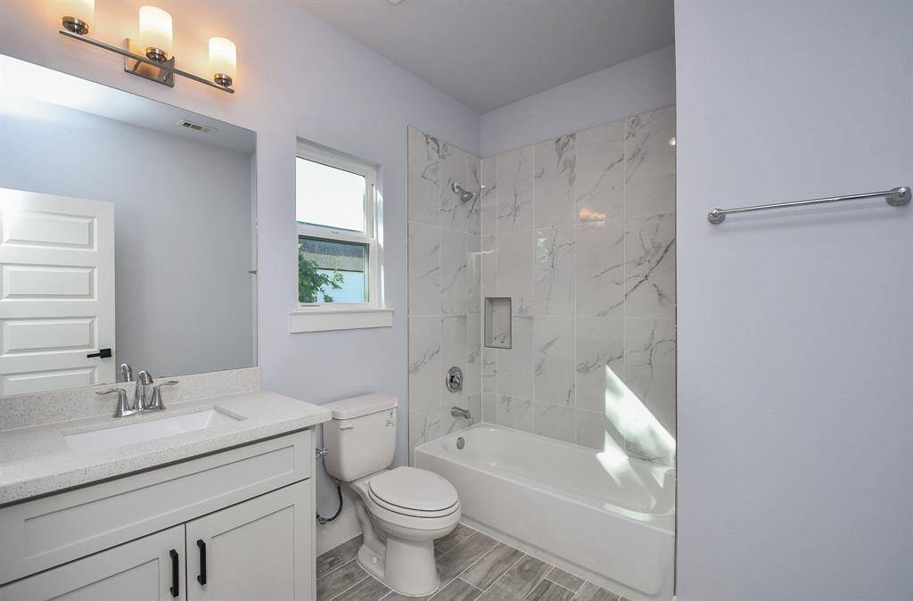 The secondary bath serving the bedrooms is beautifully appointed with quartz countertops and a luxurious shower-tub combination.