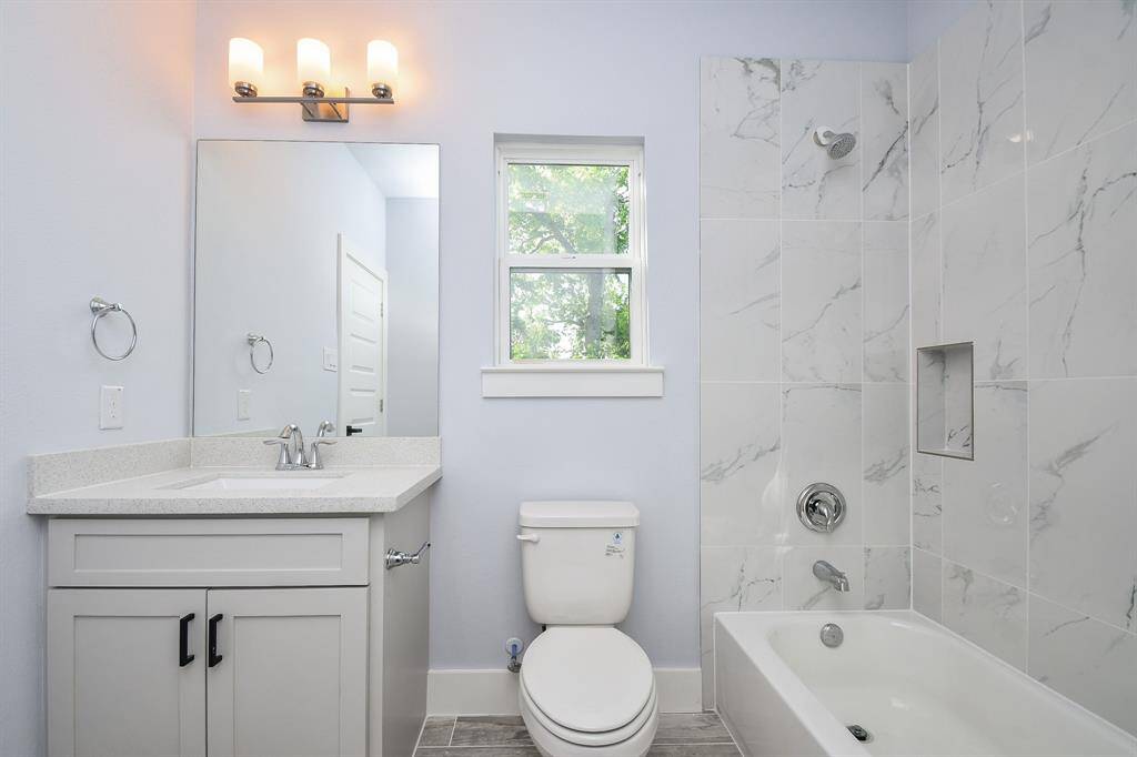 The spacious secondary bathroom is beautifully appointed, featuring quartz countertops and a shower-tub combination.