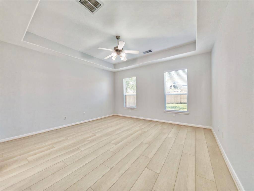 Primary bedroom has tray ceiling and two windows