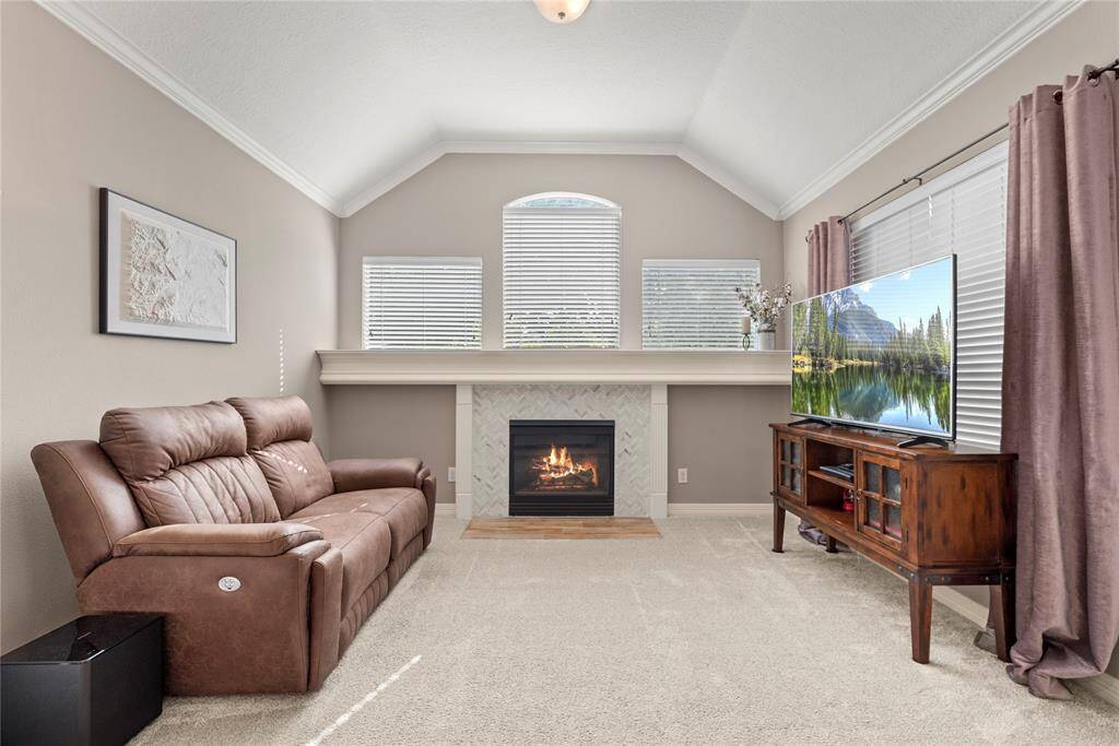 The additional sitting area in the primary bedroom offers a serene retreat, highlighted by an elegant fireplace and bathed in natural light streaming through expansive windows.