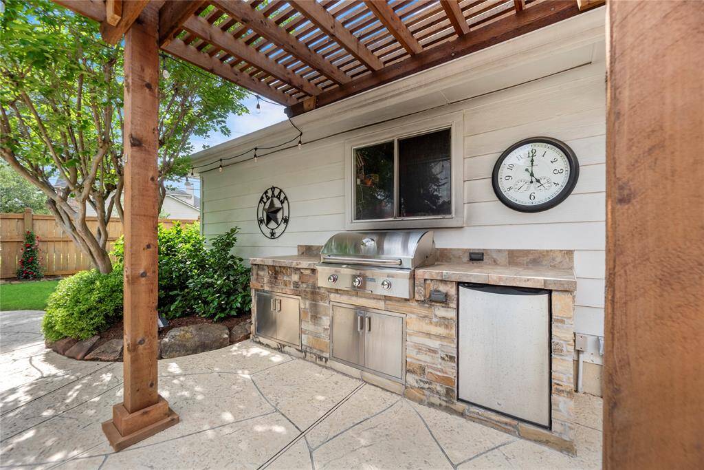 Outdoor kitchen boasts a propane grill, storage, and a mini fridge! The Pergola provides great shade for those warm Katy days.