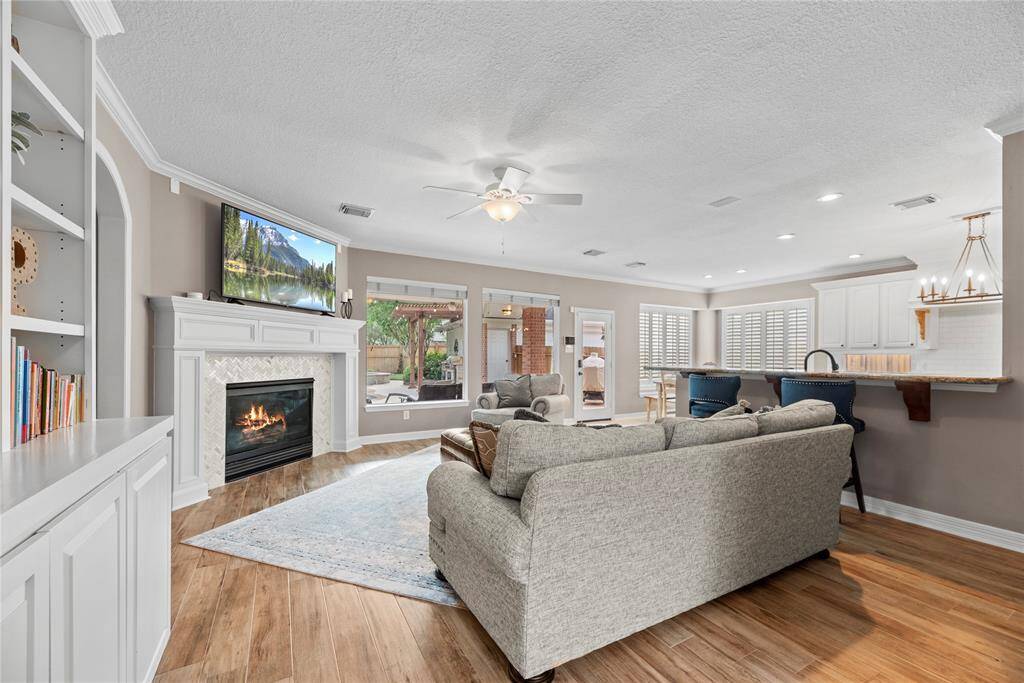The wood floors continue from the entry to the living room making the home feel open and airy. Plenty of windows allow for the view of the gorgeous backyard landscaping, pool, spa, and outdoor kitchen.