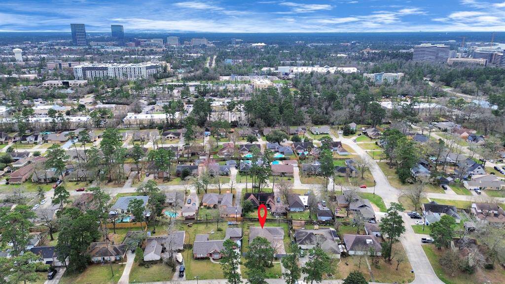 This photo showcases a suburban neighborhood with tree-lined streets and a mix of single-family homes. The area appears peaceful, with ample green space and proximity to urban amenities, visible in the distance. Ideal for those seeking a balance between tranquility and city access.