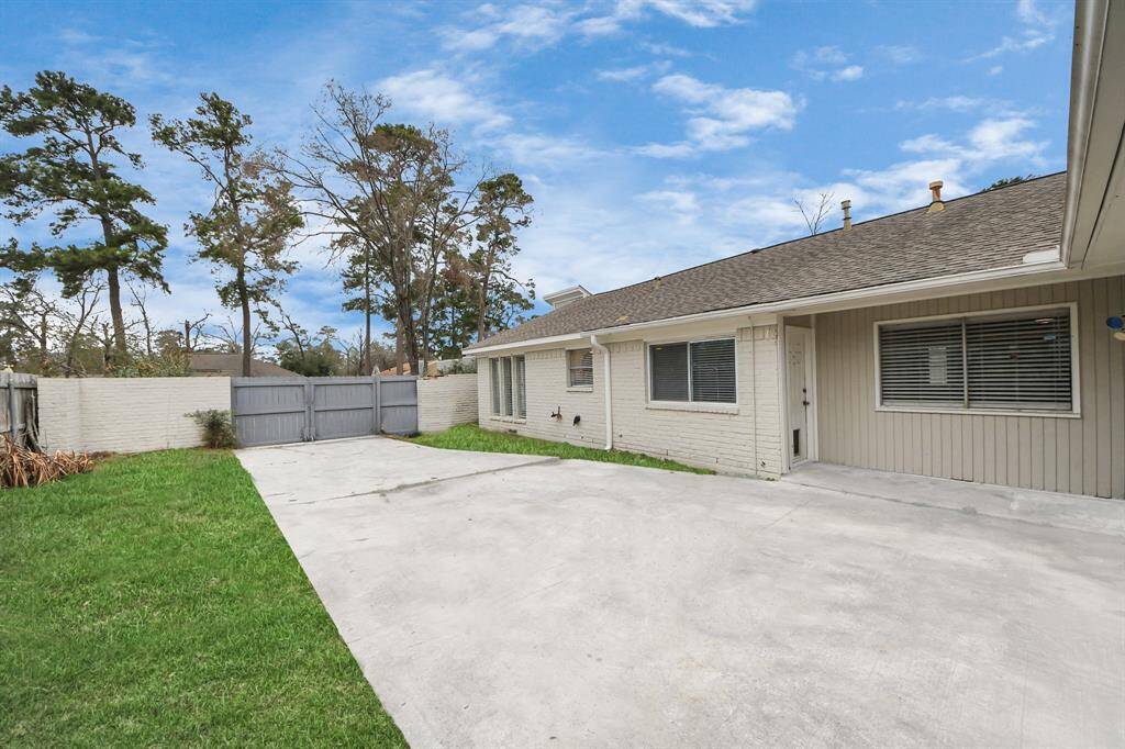 This photo showcases a spacious, fenced backyard with a concrete patio area, ideal for outdoor activities. The exterior features light-colored siding and large windows, offering a bright and welcoming atmosphere.
