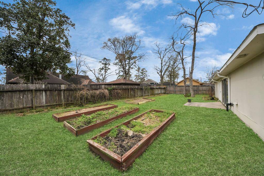 A spacious backyard with a well-maintained lawn, raised garden beds, and a wooden fence for privacy. Ideal for gardening and outdoor activities.