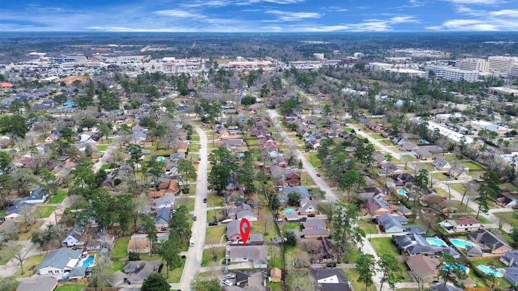 This aerial photo showcases a suburban neighborhood with tree-lined streets and a variety of homes. The area is well-developed, with accessible roads and proximity to commercial and urban centers. The marked location highlights a specific property of interest within this peaceful community.