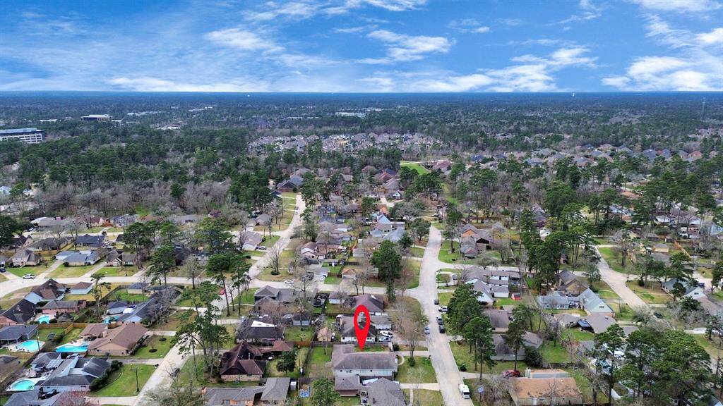 This aerial photo showcases a suburban neighborhood with a mix of single-family homes surrounded by trees. The area appears quiet and residential, with well-maintained streets and greenery. The highlighted house is centrally located, indicating a potentially convenient position within the neighborhood.