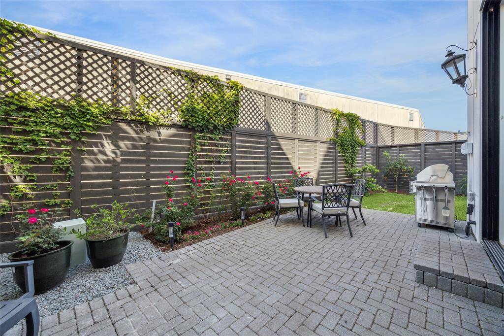 Paver covered back patio with grassy area is fenced in and offers privacy.