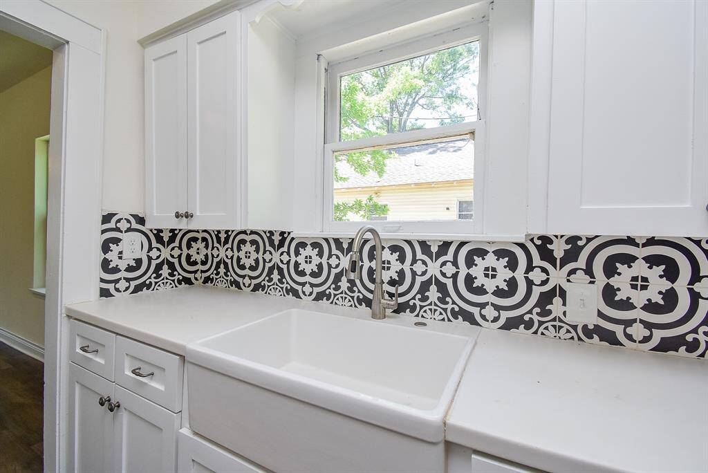 Experience the charm of a stylish farmhouse sink paired with stunning tilework and a captivating window that offers a view.