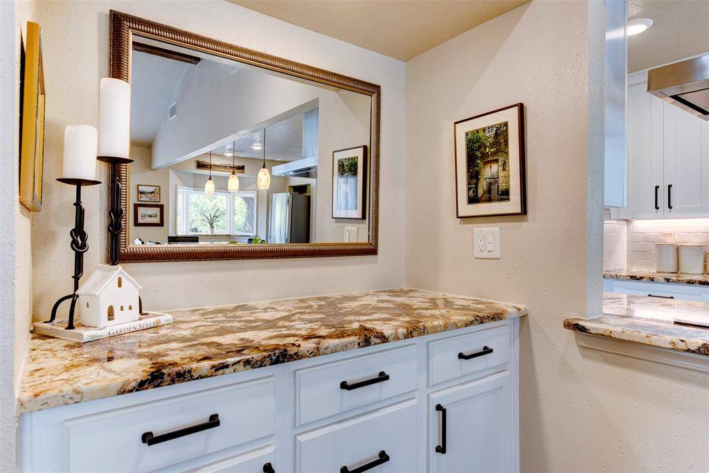 This separate built-in bar space just off the kitchen features striking granite counters, sleek dark hardware and ample cabinet space-ideal for your morning coffee or entertaining with ease.