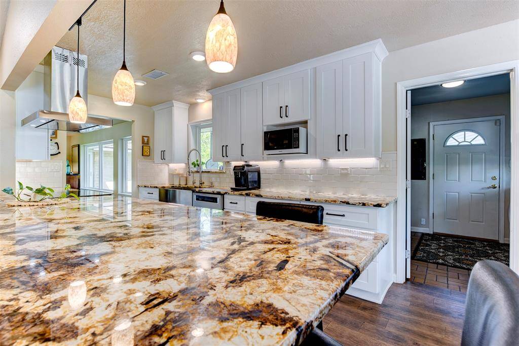 The large granite counter is a focal point. This dream kitchen offers serious prep space, storage and seating. The pendant lights lend a high-end look.