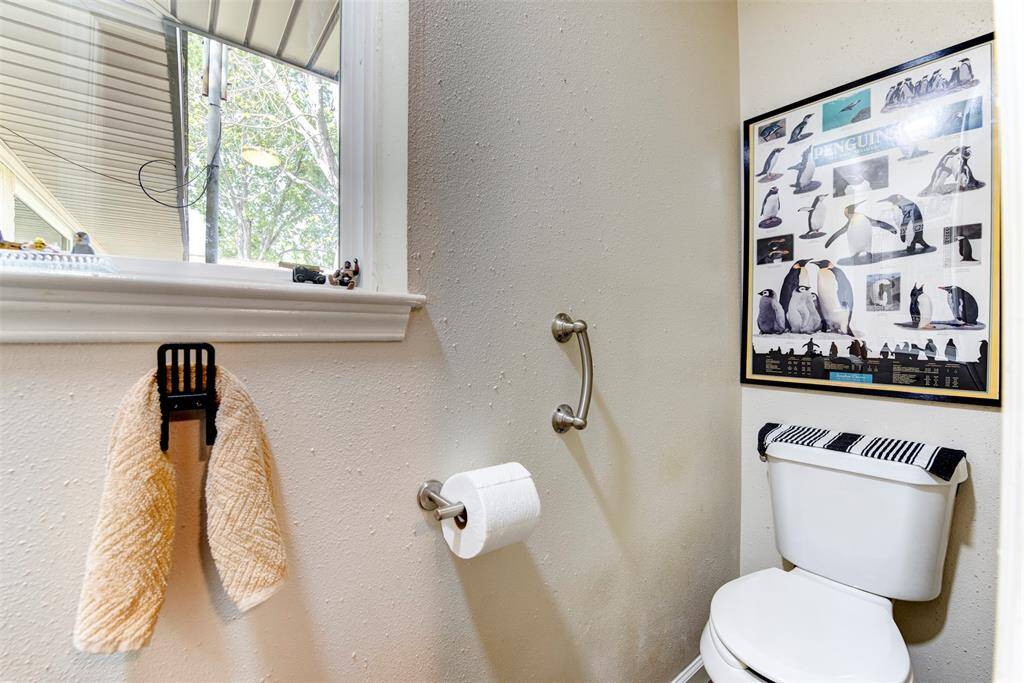 The charming powder room off the laundry room near the back door, featuring a decorative chair-style towel holder for a unique touch.