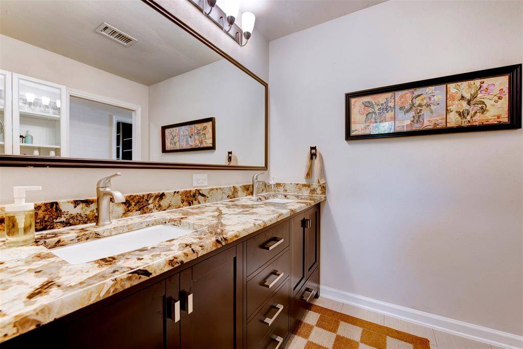 This spacious guest bath features a dual sink vanity with rich granite countertops and updated features.