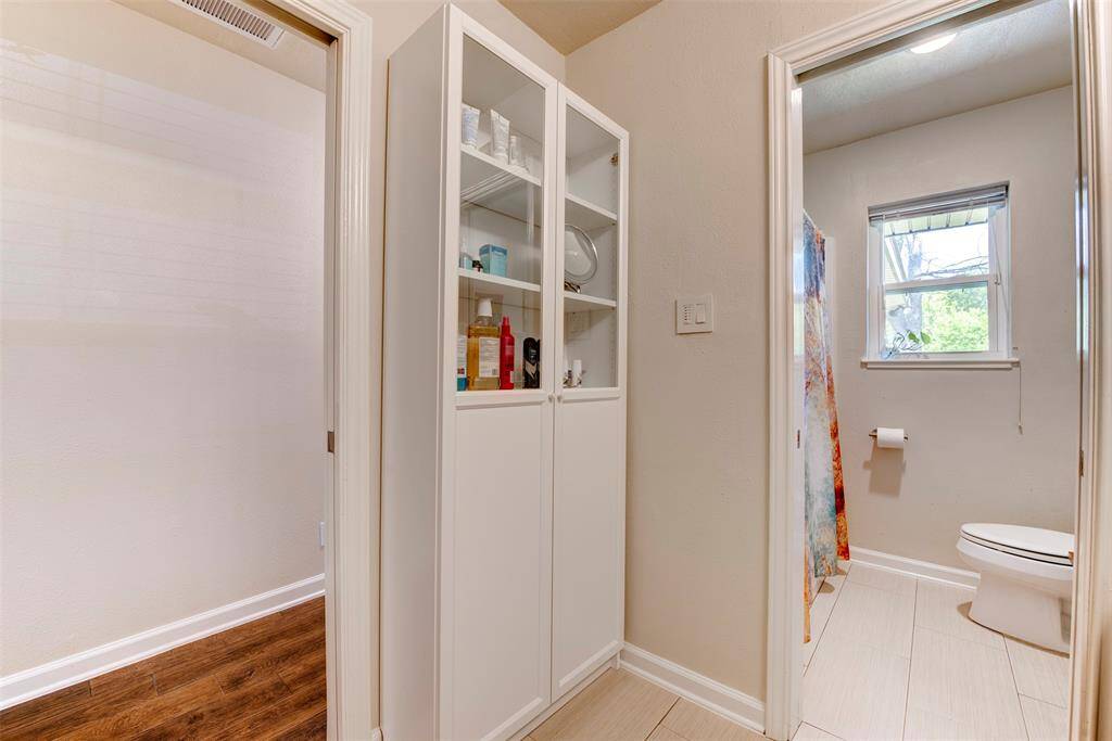 A glass front storage cabinet offers both function and charm, perfect for displaying towels or essentials.