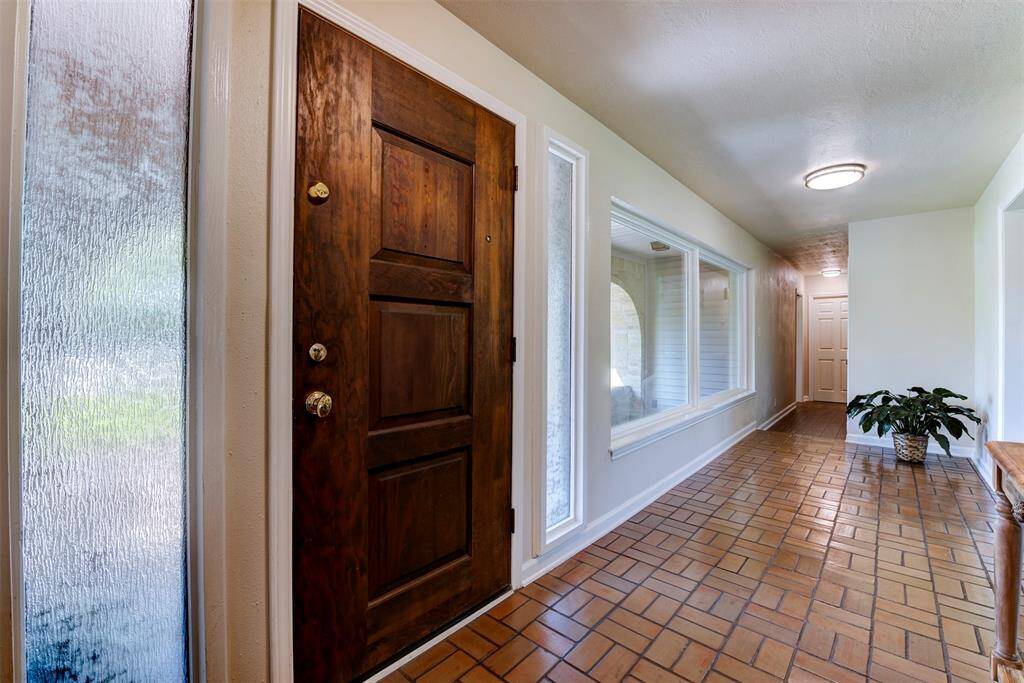 Warm and welcoming entryway with a solid wood front door, sidelight glass panels for natural lighting that flows through the foyer.