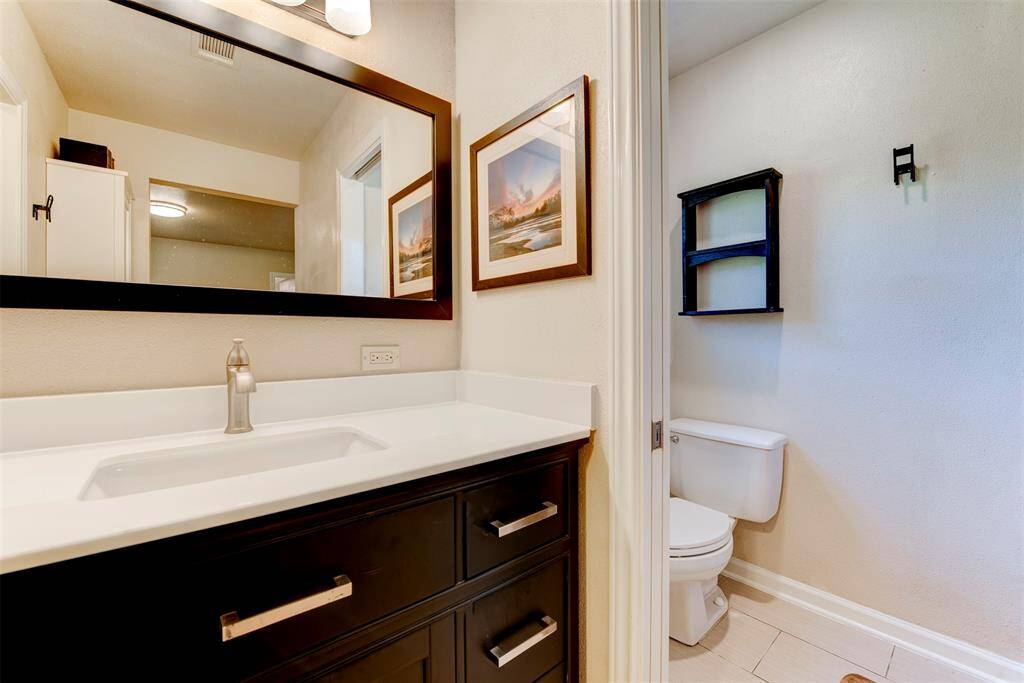 The primary bath features a sleek dark wood vanity topped with a white solid surface countertop and under  mount sink.